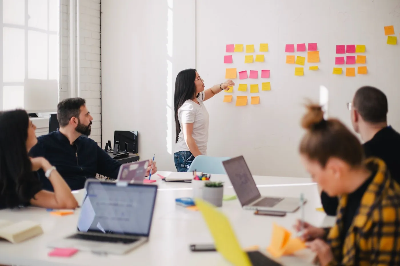 Een team ontwerpt samen een proces met post-its op de muur